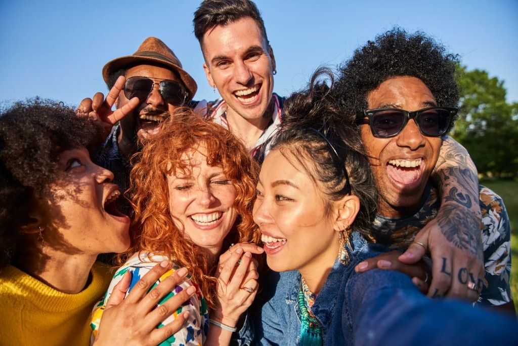 Diverse group of friends laughing together outdoors in warm sunlight